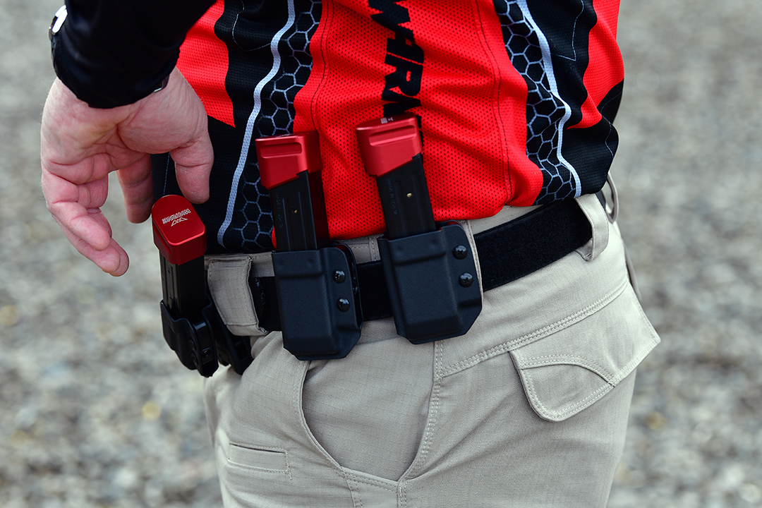 USPSA competitive shooter reaching for magazine with Warne mag extension.