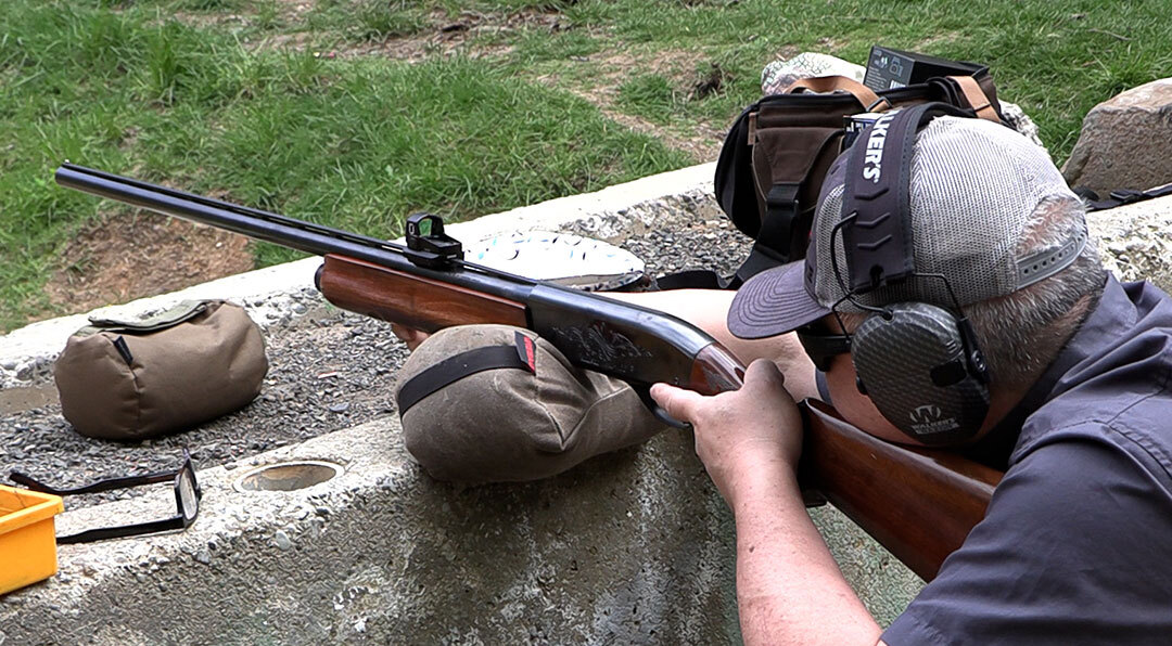Man shooting a Remington 1100 with a red dot on it